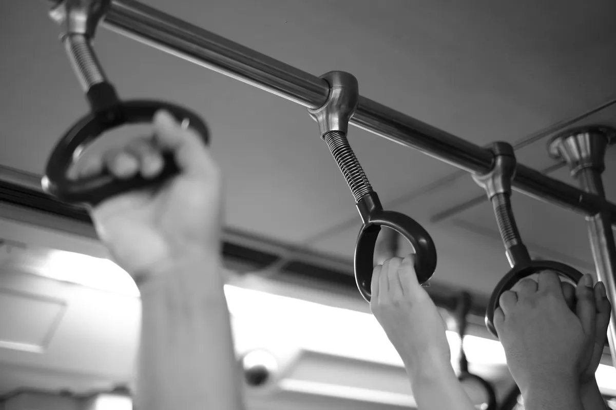 Hands gripping gymnastic rings and a bar seen from below in black and white